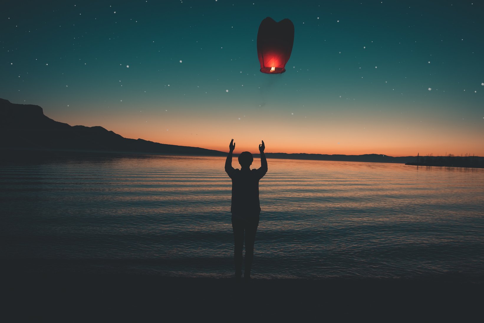 Silhoette of Person Releasing Red Paper Japanese Lantern